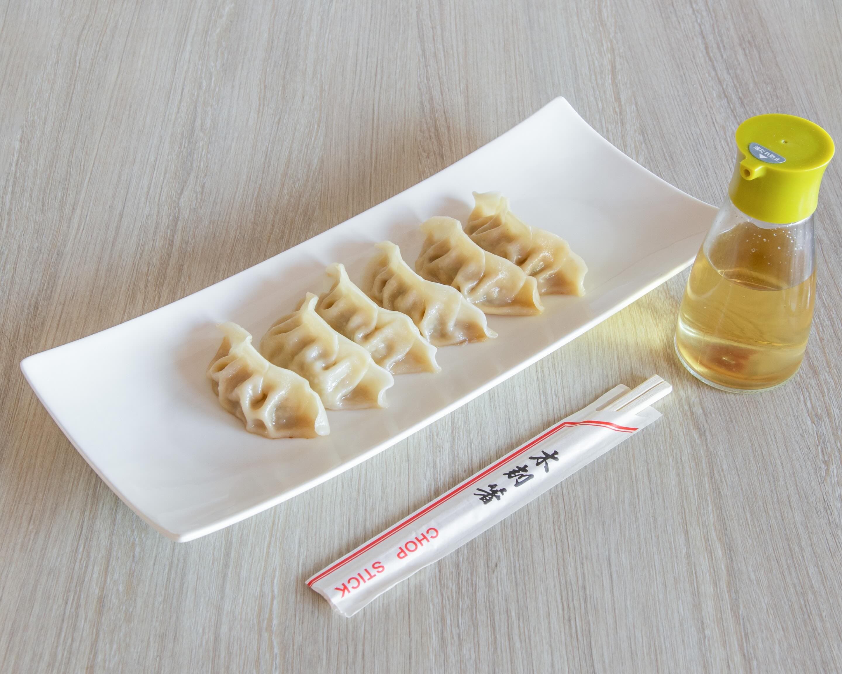 A plate of dumplings with dipping sauce
